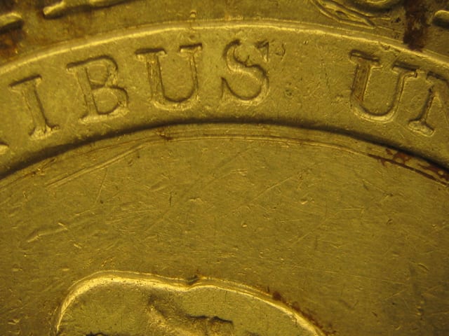 A more significant scratch under the banner on the reverse of the Capped Bust half dollar in Figure 4 is less noticeable because it blends closely with the design and has toned down over time.