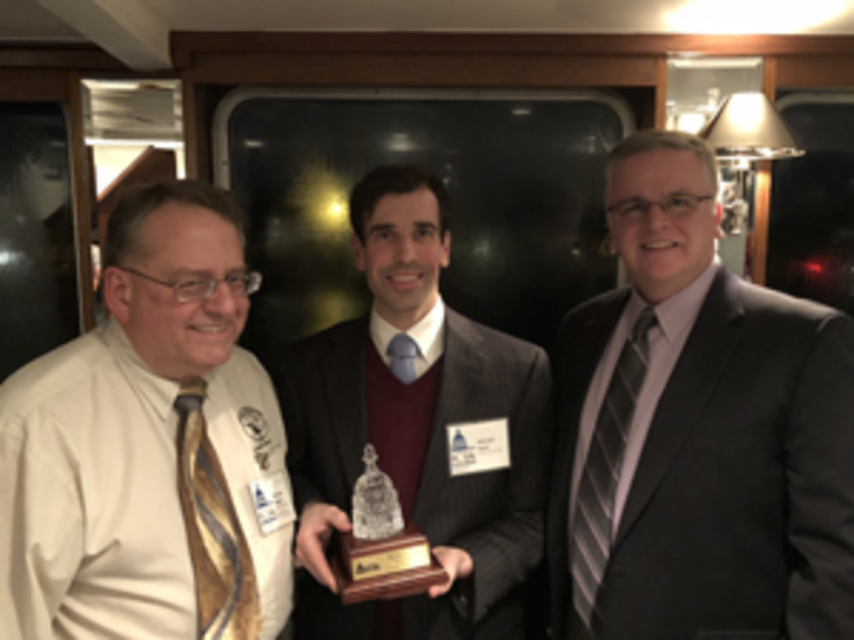  Industry Council for Tangible Assets chief operating officer David Crenshaw (right) and ICTA treasurer Patrick Heller (left) present Mitch Hyatt (center) with the Diane Piret Award.