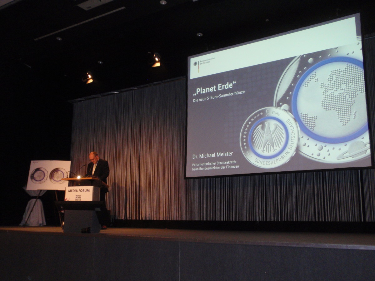 Both old and new were on display at the introduction of the German 5-euro Planet Earth coin. A easel was next to Dr. Michael Meister as well as the large screen multi-media projection system.