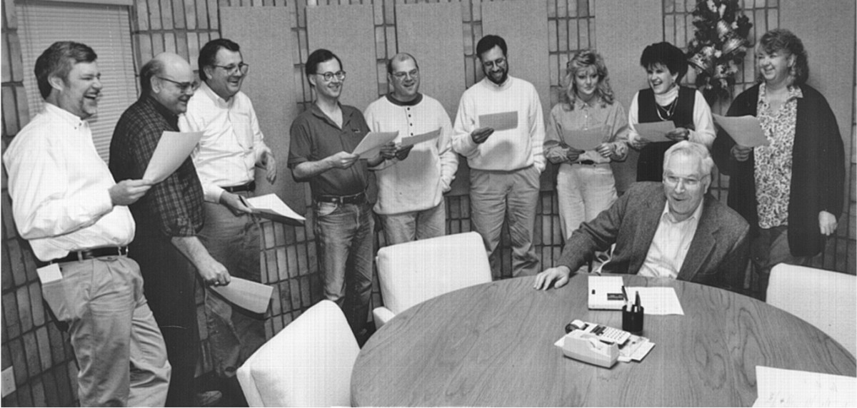 David Harper, fourth from left, joins fellow Krause Publications staff in singing “O Lutefisk,” a holiday tradition at the Iola, Wis., office. They share a smile with Chet Krause, seated.